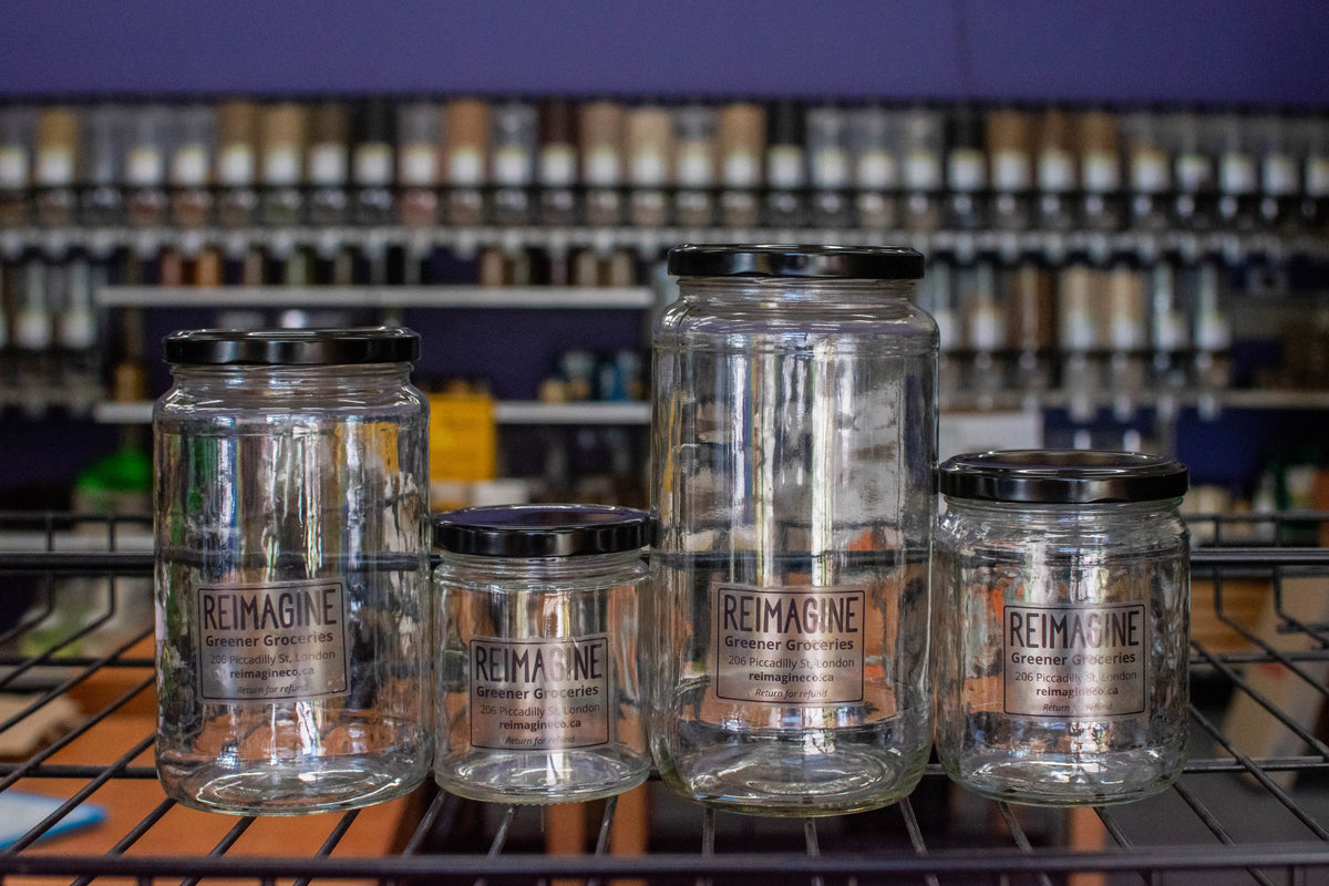 empty glass jars on a metal shelf with grocery refill stations behind