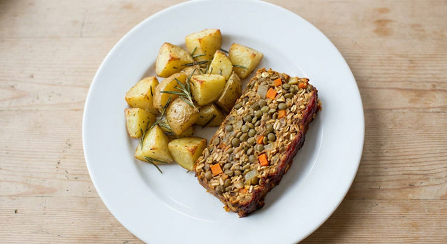 Slice of vegan lentil loaf with roasted rosemary potatoes on a white plate